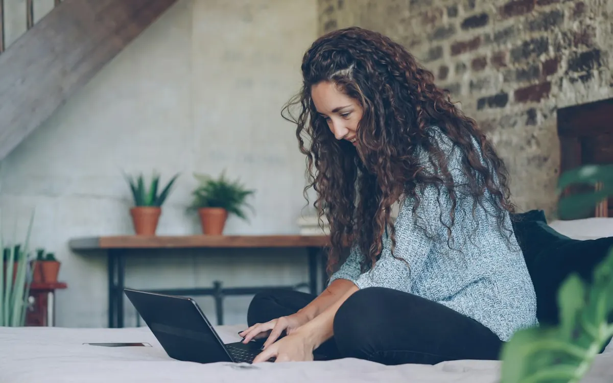 Mulher usando notebook no quarto do apartamento com Wi-Fi est&aacute;vel